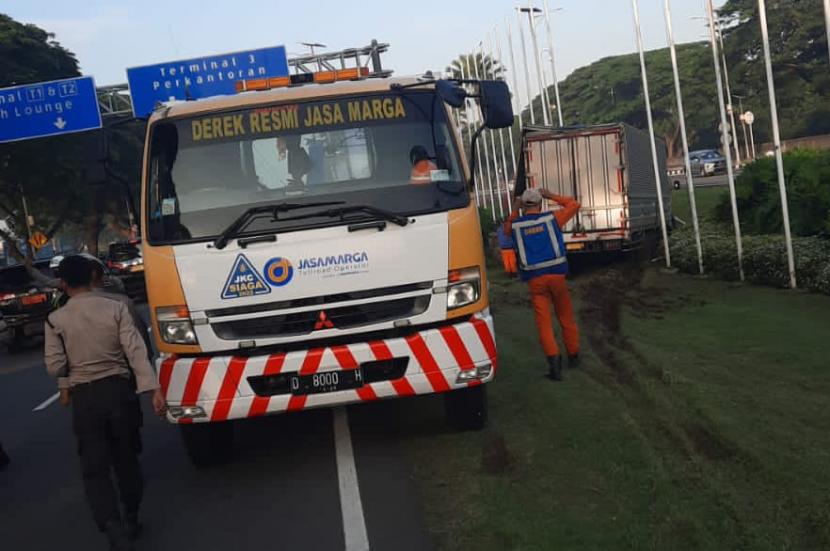Mobil derek Jasa Marga mencoba menarik truk yang masuk parit di pintu masuk Bandara Soekarno-Hatta, Kota Tangerang, Provinsi Banten, Jumat (10/3/2023).