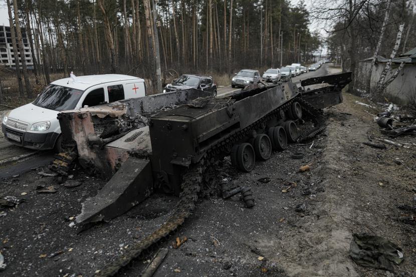 Mobil melewati tank Rusia yang hancur saat konvoi kendaraan yang mengevakuasi warga sipil meninggalkan Irpin, di pinggiran Kyiv, Ukraina, Rabu, 9 Maret 2022. 