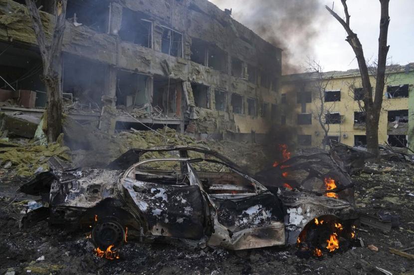 Mobil terbakar di sebelah gedung rumah sakit bersalin yang hancur diserang Rusia, di Mariupol, Ukraina, 9 Maret 2022.
