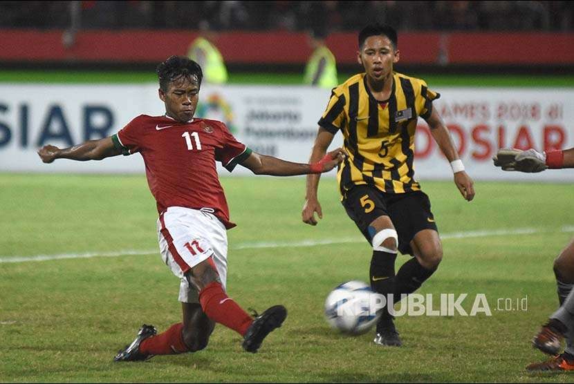 Mochammad Supriadi (kiri) berusaha melepaskan tendangan melewati hadangan pesepak bola Malaysia U-16 Mohamad IkhwanMohd Hafizd (kanan) pada laga semifinal Piala AFF U-16