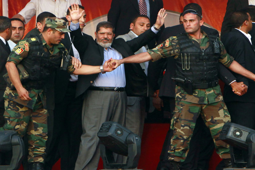 Mohamed Mursi (tengah) melambaikan tangan ke para pendukungnya saat ditahan oleh anggota keamanan presiden di Tahrir Square, Kairo, Mesir, pada 29 Juni 2012. (file foto). 