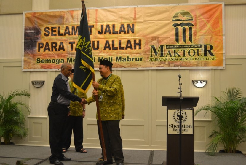 Mohammad Rocky Masyhur, pimpinan Maktour menyerahkan bendera Maktour pada pembimbing Maktour Ustaz Hafiz dan Ustaz Faishol Muzammil