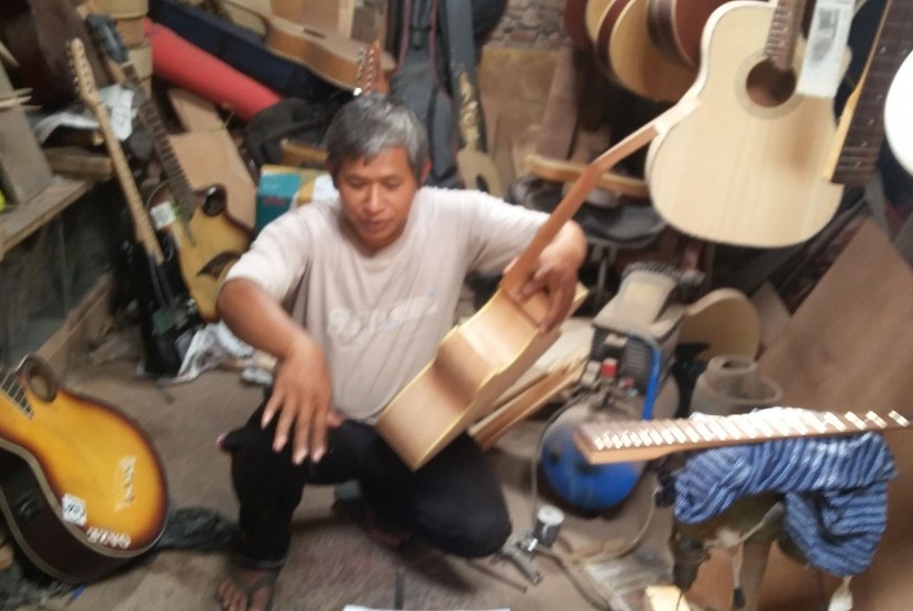 Mokhammad Fauzi, salah satu perajin gitar asal Malang, Jawa Timur, sedang menyelesaikan pembuatan pesanan gitar akustik.