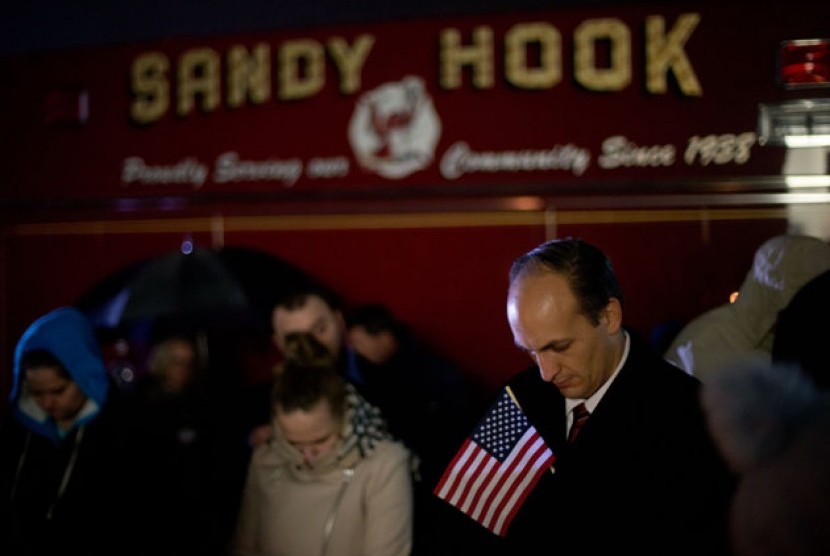Mourners listen to a memorial service over a loudspeaker outside Newtown High School for the victims of the Sandy Hook Elementary School shooting, Sunday, Dec. 16, 2012, in Newtown, Conn.  