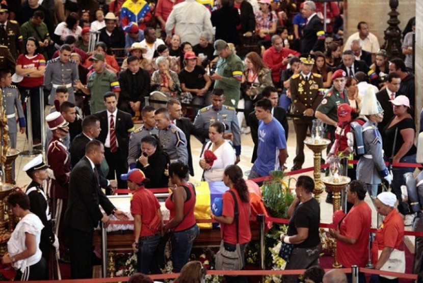 Mourners walk beside the coffin containing the body of Venezuela's late President Hugo Chavez on display during his wake at a military academy where his body will lie in state until his funeral in in state in Caracas, Venezuela, Thursday, March 7, 2013. 