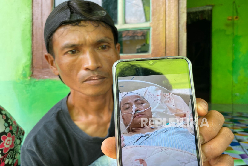 Mujahid (40), menunjukkan foto istrinya, Marini (38), yang terbaring di rumah sakit di Taiwan setelah terjatuh di kamar mandi. Warga Desa Tinumpuk, Kecamatan Juntinyuat, Kabupaten Indramayu itu meminta bantuan kepada Presiden Prabowo, Gubernur Jabar, Dedi Mulyadi dan Bupati Indramayu, Lucky Hakim. 