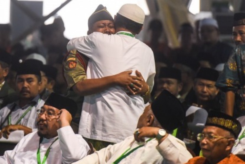 Muktamirin berpelukan dengan sorang anggota Banser seusai Rais Aam PBNU Mustofa Bisri memberikan fatwa saat pembahasan rancangan Tatib Muktamar NU ke-33 di alun-alun Jombang, Jawa Timur, Senin (3/8).