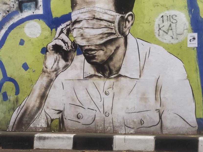 Mural mirip Presiden Jokowi dengan mata ditutup masker berukuran dua meter terpampang di dinding flyover Pasupati Bandung, Rabu (25/8). Bagian jari tangannya sedang memegang masker yang dipakainya. Mural tersebut saat ini sedang dihapus.