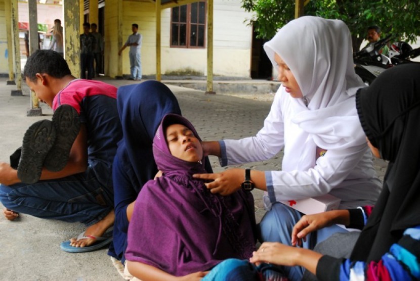 Murid sekolah membantu mengobati temannya yang terluka saat simulai gempa dan tsunami yang digelar mahasiswa Universitas Syiah Kuala (Unsyiah)