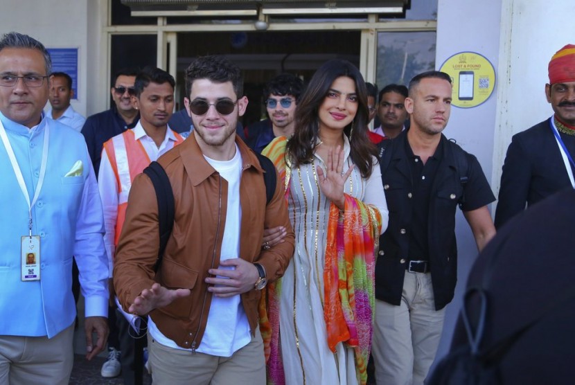 Musisi Nick Jonas (berkacamata hitam) dan aktris Priyanka Chopra tiba di bandara di Jodhpur, Rajashtan, India, (29/11). Keduanya berada di India untuk melangsungkan pernikahan.