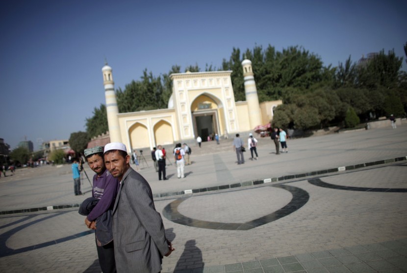 Muslim etnis Uighur berjalan di depan sebuah masjid di Kashgar, Xinjiang, Cina.