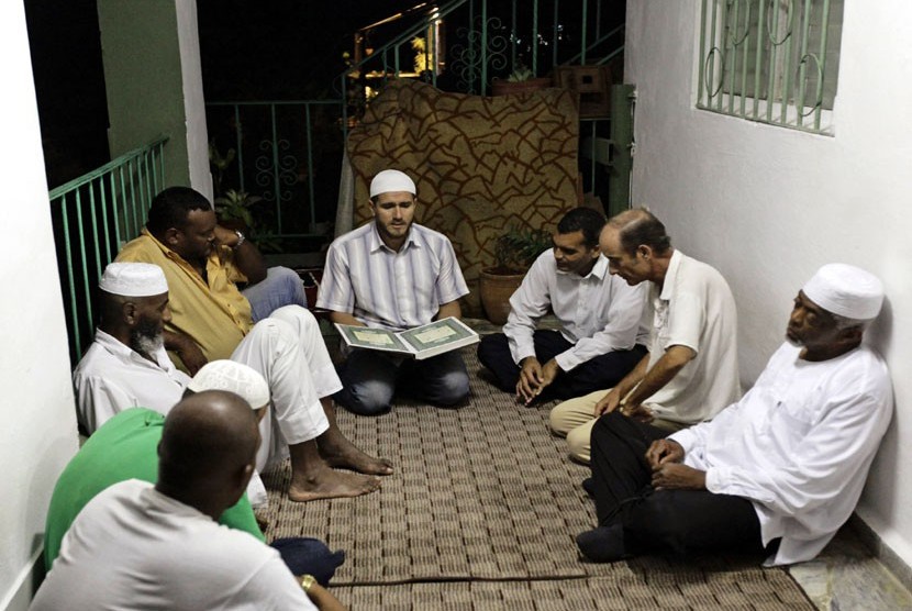  Muslim Kuba mendengarkan pembacaan ayat suci Alquran usai makan Iftar atau buka puasa bersama di Havana, Cuba, Jumat (3/8).   (Desmond Boylan/Reuters)