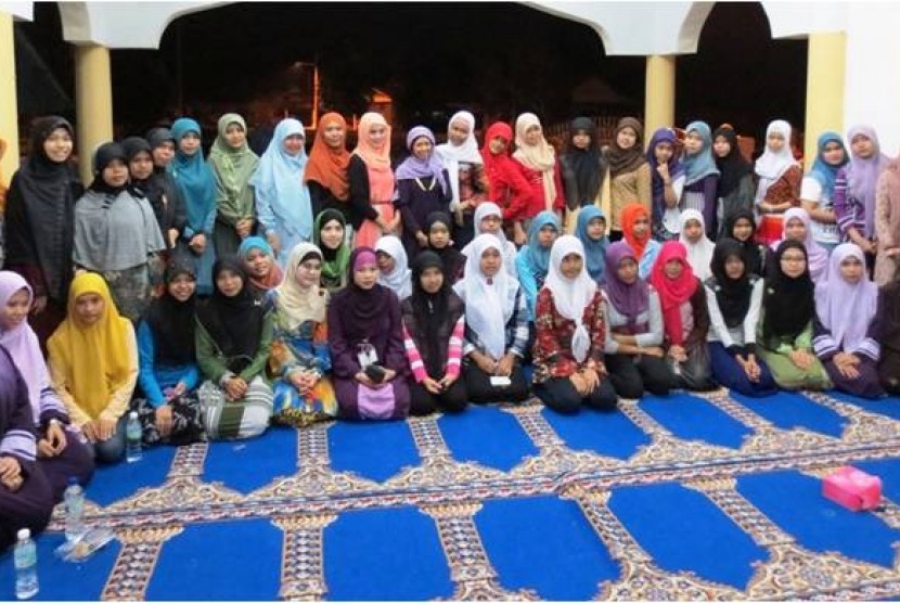 Muslimah dari Universiti Teknologi Petronas (UTP) berfoto bersama pekerja pabrik di Perak, Malaysia.