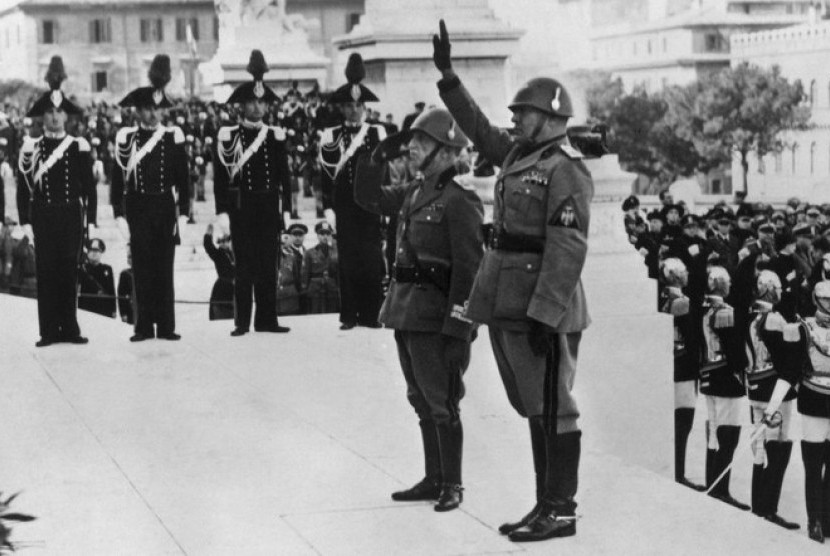Musolini (kanan) dan Raja Emmanuel (kiri) memberi hormat pada monumen pahlawan tak dikenal  pada tahun 1938 di Roma.