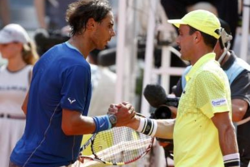 Nadal berbaju biru berjabat tangan dengan Baut setelah memenangkan pertandingan dan maju ke final Madrid Masters.