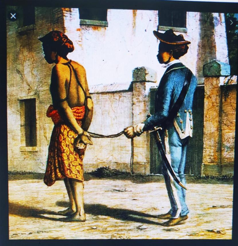 Narapidana dengan tangan terikat rantai di bawa ke tiang gantungan untuk menjalani hukuman mati pada masa kolonial Belanda.