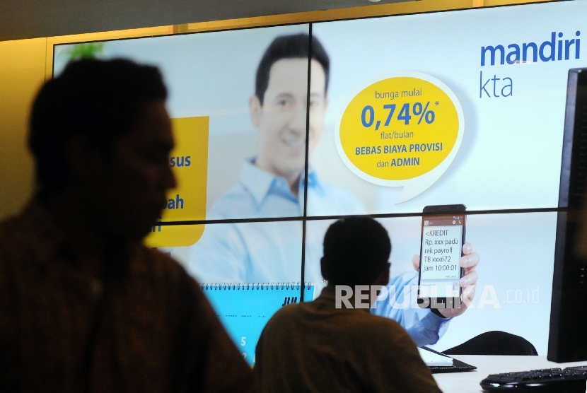 Nasabah melintasi banner iklan penawaran kredit tanpa agunan (KTA) yang ditawarkan di salah satu kantor cabang Bank Mandiri, Jakarta.