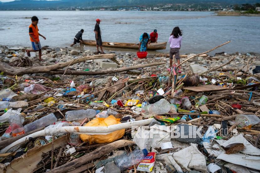 Nelayan beraktivitas di dekat tumpukan sampah plastik yang mencemari muara sungai di Palu, Sulawesi Tengah, Jumat (2/4/2020). Pemerintah setempat kesulitan menangani sampah plastik yang mencemari muara sungai tersebut karena sebagian besarnya adalah bawaan dari air laut ketika pasang.