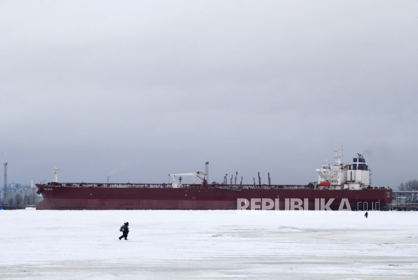 Nelayan berjalan sambil memancing di es di Teluk Finlandia di depan kapal tanker minyak mentah Sea Luck III, di St. Petersburg, Rusia, 24 Januari 2024. Ini keuntungan bergabungnya Indonesia di BRICS, salah satunya bisa mendapatkan akses minyak mentah dari Rusia.