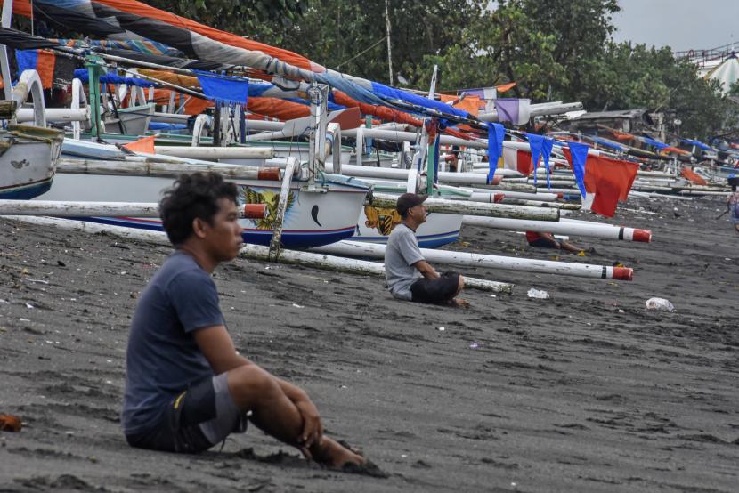 Nelayan duduk menatap ombak di pinggiran Pantai Ampenan, Kota Mataram, Nusa Tenggara Timur (NTB)