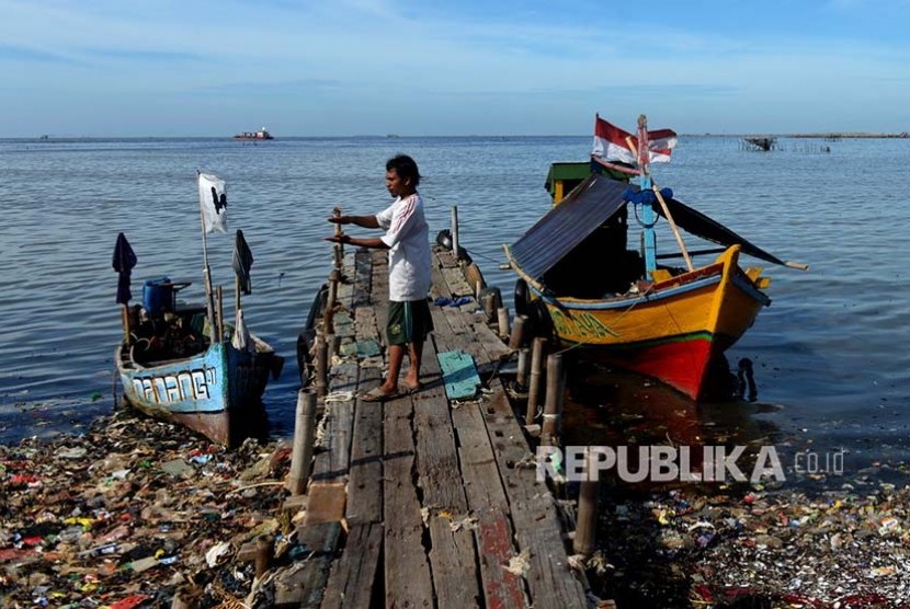 Nelayan kerang hijau Muara Angke menambatkan perahunya di dermaga. Di garis cakrawala proses reklamasi telah menggusur tempat-tempat peterenakan kerang hijau di Teluk Jakarta.