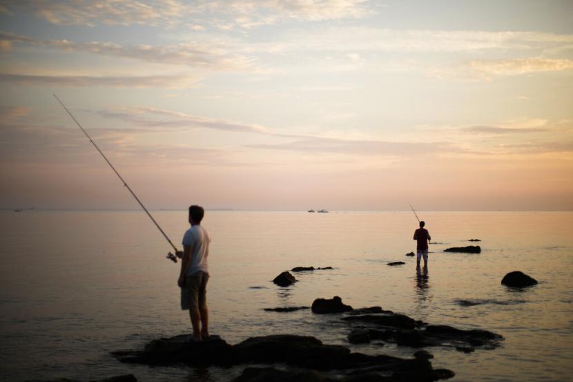 Nelayan melemparkan pancing ke Laut Aegea saat matahari terbenam di desa Seddulbahir, Turki, Jumat, 2 September 2022.