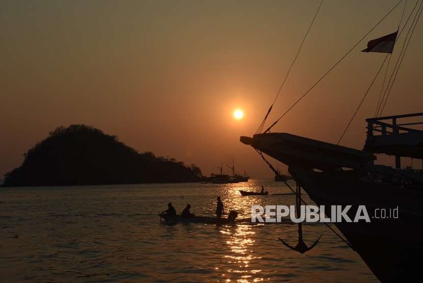 Nelayan melintas saat matahari tenggelam di perairan Labuan Bajo, Manggarai Barat, Nusa Tenggara Timur, Jumat (12/10).