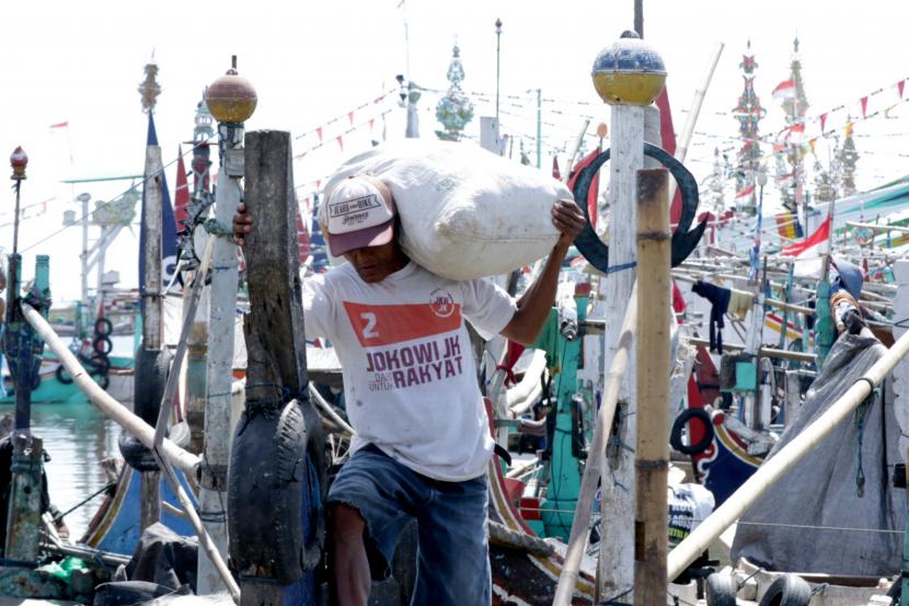 Nelayan memakai masker memanggul barang bawaannya di Pelabuhan Ikan Muncar Banyuwangi, Jawa Timur.