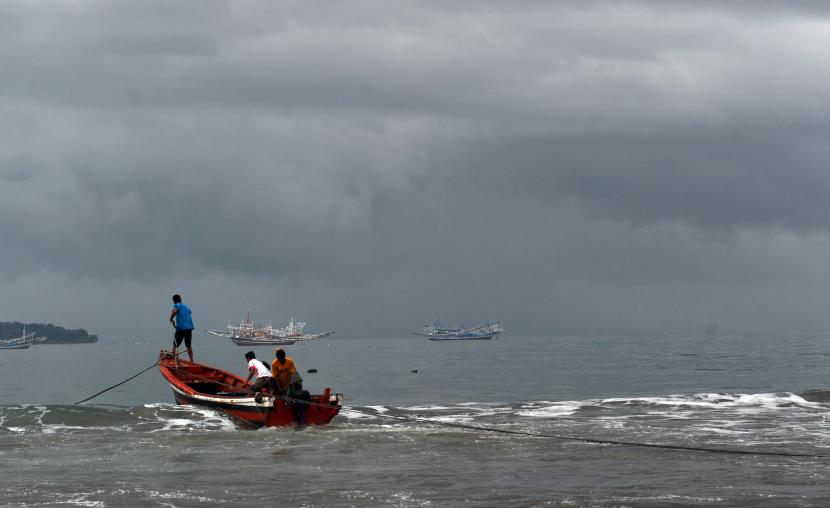Nelayan memindahkan bahan bakar untuk kapal bagan saat langit berawan di Pantai Pasie Nan Tigo, Padang, Sumatera Barat.