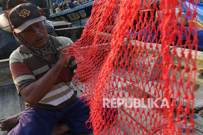 Nelayan memperbaiki jaring di Cilincing, Jakarta,