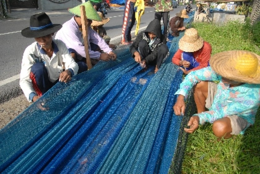 Nelayan memperbaiki jaring pukat harimau, di Jalan Raya Pamekasan-Sampang Desa Bandaran, Tlanakan Pamekasan, Jatim, Selasa (3/2)
