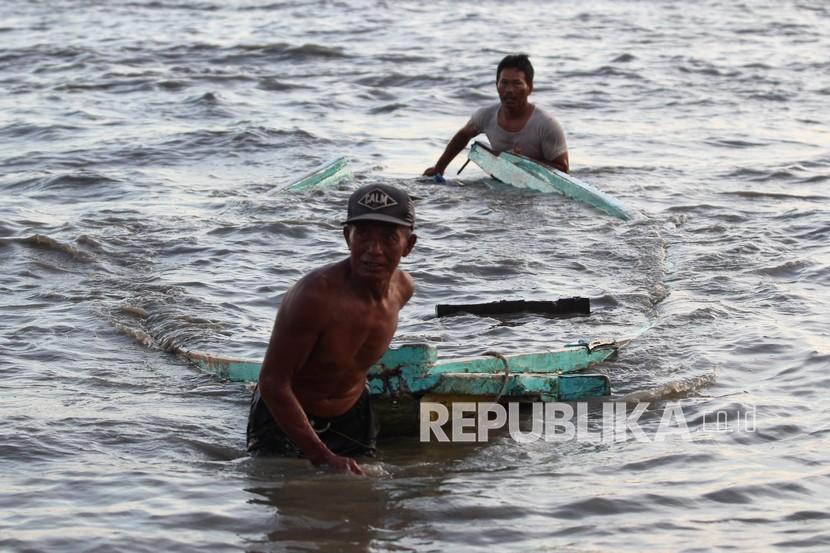 Nelayan mengevakuasi perahunya yang pecah akibat terhantam gelombang laut. (Ilustrasi)