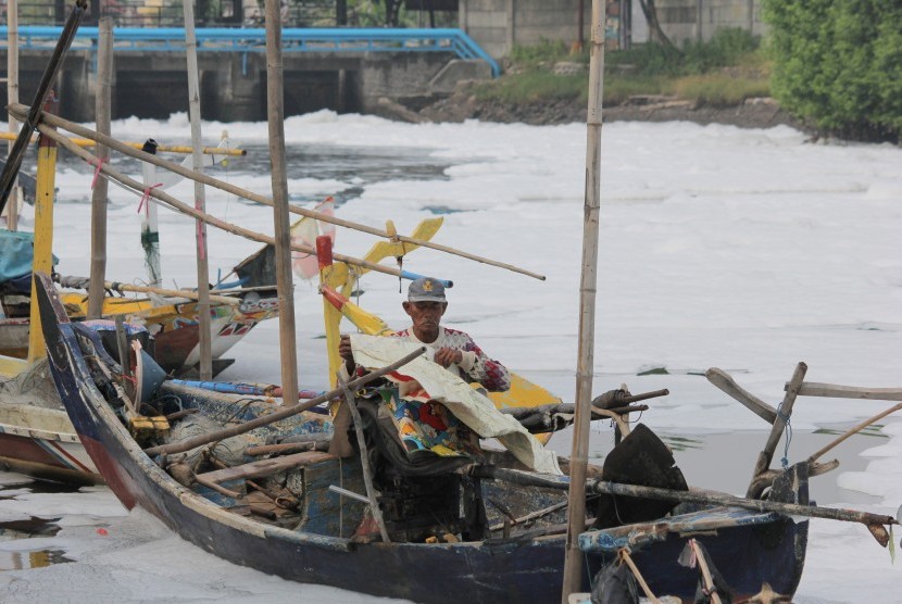 Nelayan menutup mesin perahu di sekitar muara Sungai Tambak Wedi yang dipenuhi limbah busa putih di Surabaya, Jawa Timur, Senin (21/3).