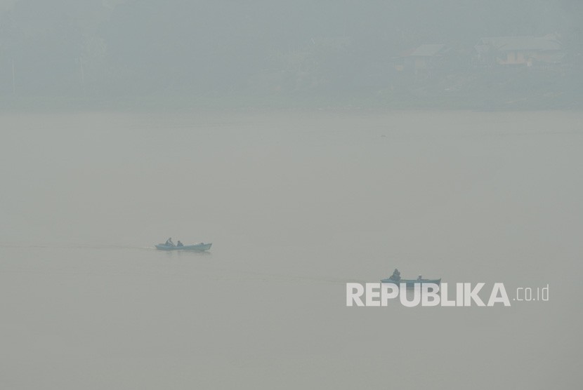 Nelayan menyusuri Sungai Batanghari yang diselimuti kabut asap kebakaran hutan dan lahan (karhutla), Jambi, Selasa (15/10/2019).