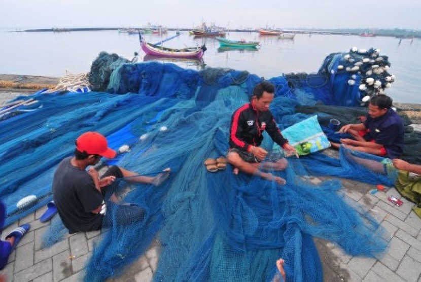 Nelayan yang tidak melaut memperbaiki jaring di Pelabuhan Branta Pesisir, Tlanakan, Pamekasan, Jawa Timur, Selasa (28/11). Sebagian nelayan di daerah itu tidak melaut menyusul peringatan BMKG terkait Badai Siklon Tropis yang meliputi sejumlah daerah di Indonesia termasuk Jawa Timur dengan potensi tinggi gelombang antara 2,5 meter hingga enam meter.