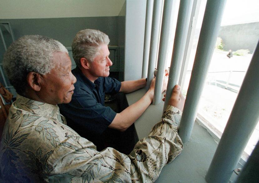 Nelson Mandela (kiri) dan mantan Presiden AS Bill Clinton melihat keluar dari jendela sel Mandela di Robben Island, Cape Town, Afsel, 27 Maret 1988. Pemerintah Afrika Selatan, Jumat (24/12), mendesak pembatalan lelang kunci sel Mandela. 