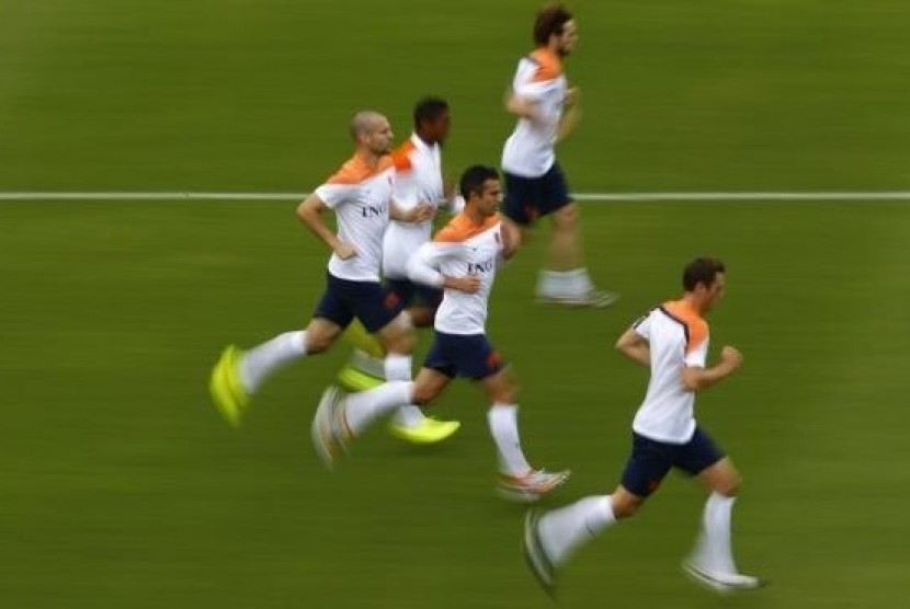 Netherlands' Robin Van Persie (center) and Ron Vlaar (left) run with teammates during a training session in Rio de Janeiro June 19, 2014.