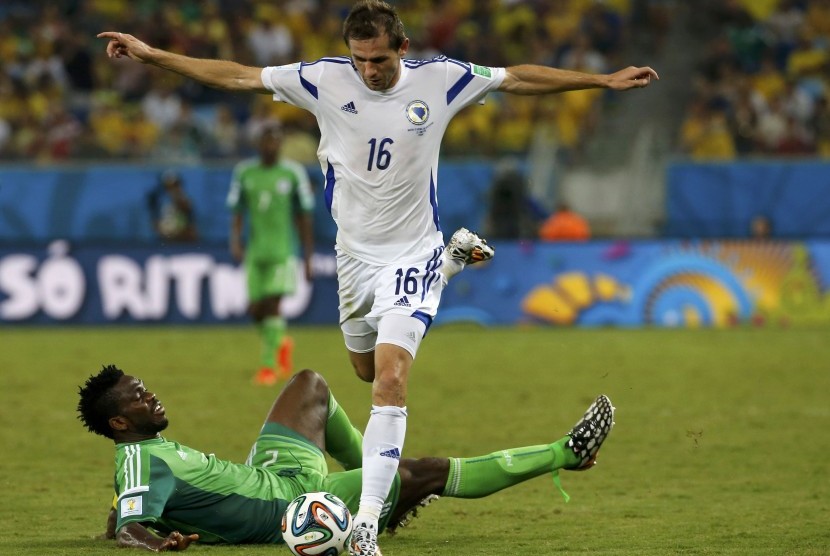 Nigeria's Joseph Yobo falls to the ground as Bosnia's Senad Lulic goes for the ball during their 2014 World Cup Group F soccer match at the Pantanal arena in Cuiaba June 21, 2014.