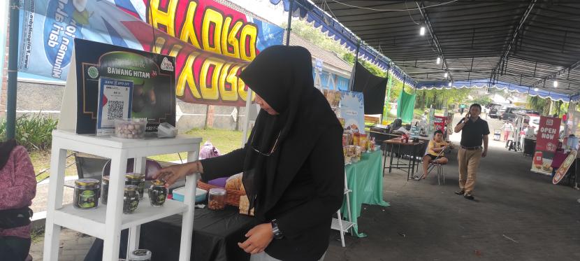 Niken Parwati Kinanti, salah satu peserta Mojog Fest di taman kuliner, Depok, Sleman, sedang mempromosikan produk bawang hitam ke pelanggan. 