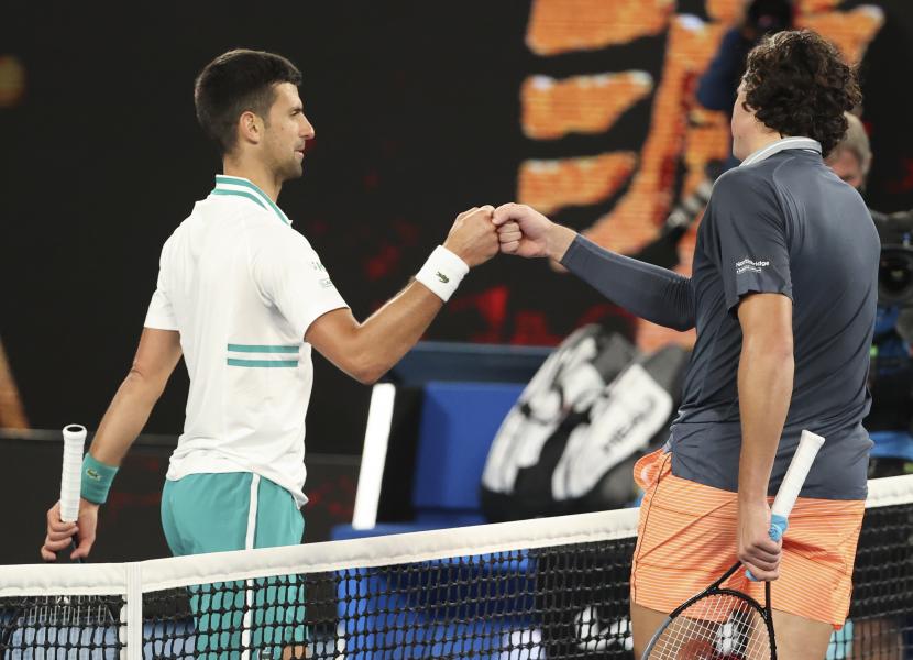Novak Djokovic dari Serbia (kiri) diberi selamat oleh Milos Raonic dari Kanada setelah memenangkan pertandingan putaran keempat di kejuaraan tenis Grand Slam Australia Terbuka di Melbourne, Australia, Senin, 15 Februari 2021.