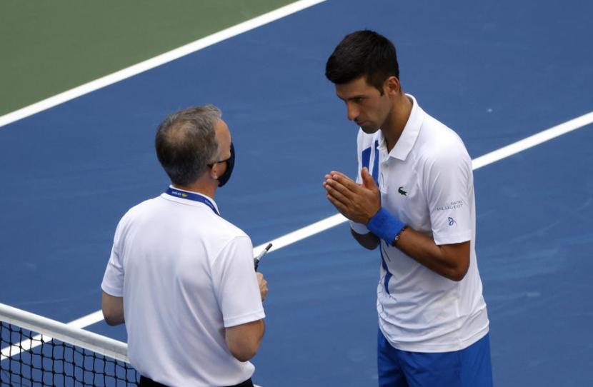 Novak Djokovic (kanan) berbicara dengan Kepala Wasit ITF Soeren Friemel setelah ia tak sengaja memukul bola mengenai hakim garis wanira dalam pertandingan US Open 2020 melawan Pablo Carreno Busta di USTA National Tennis Center, Flushing Meadows, New York, AS, Senin (7/9) dini hari WIB.
