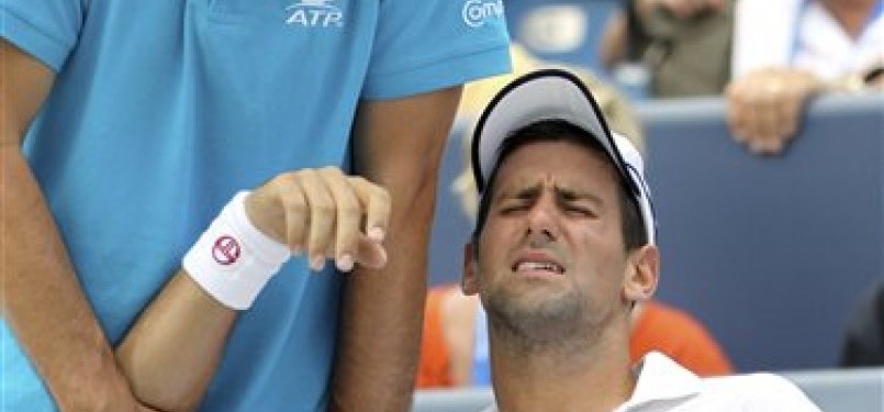Novak Djokovic (kanan) mengerang kesakitan saat mendapat perawatan dari pelatih Hugo Gravil. 