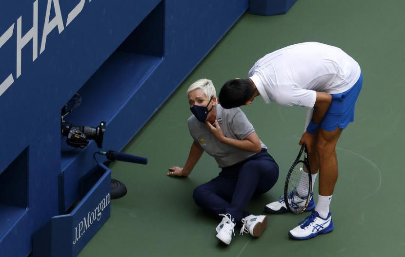 Novak Djokovic (kanan) menghampiri ofisial pertandingan Grand Slam US Open yang terkena bola yang dipukullkannya saat menghadapi Pablo Carreno Busta. Bola mengenai tenggorokan sang ofisial perempuan dan Djokovic kemudian didiskualifikasi dari US Open.