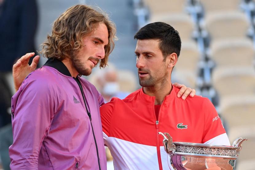 Novak Djokovic (kanan) menghibur Stefanos Tsisipas yang dikalahkannya pada final French Open 2021, Senin (14/6).