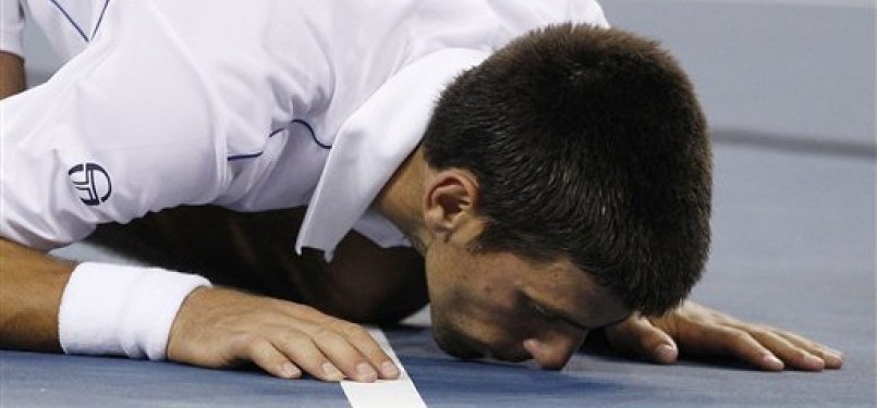 Novak Djokovic mencium lapangan usai memastikan juara Amerika Terbuka dengan mengalahkan Rafael Nadal di partai final.
