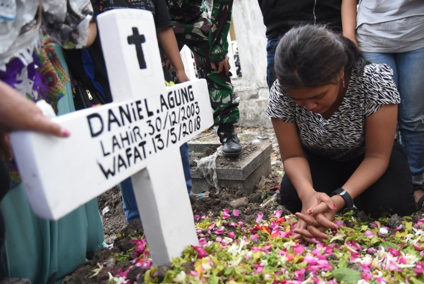 Novi (kanan) kakak dari Daniel Agung Putra Kusuma korban bom bunuh diri di Gereja Pantekosta Pusat Surabaya (GPPS) berada disamping pusara ketika pemakaman di Makam Putat Gede Surabaya, Jawa Timur, Selasa (15/5). 