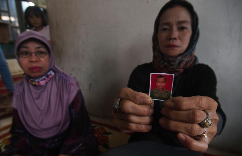 Nur Aisyah istri (kanan) salah seorang korban penembakan kelompok kriminal bersenjata (KKB) menunjukan foto suaminya Mahmud Ismaun saat ditemui di rumah duka di Palu, Sulawesi Tengah, Ahad (17/7/2022). Jenazah Mahmud Ismaun yang merupakan salah satu dari delapan korban penembakan KKB di Papua dan dijadwalkanjenazah korban akan tiba di Kota Palu pada Senin (18/7/2022) dan akan dimakamkan dipemakaman keluarga. 