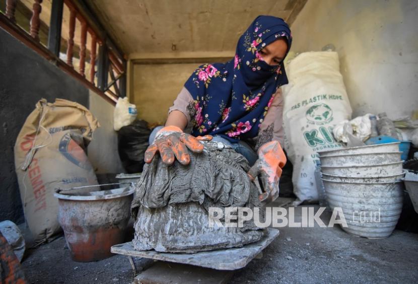 Pekerja mencetak sampah popok bayi yang telah dibasahi dengan adonan semen untuk dijadikan pot bunga di rumahnya di Dusun Belencong, Desa Midang, Kecamatan Gunungsari, Lombok Barat, NTB, Sabtu (13/3).