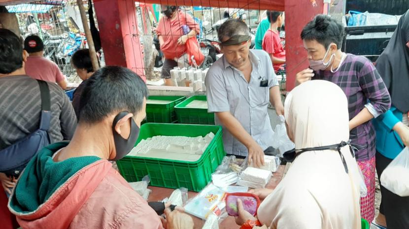 Nyoto Prawiro sedang membungkus tahu pesanan pembeli di lapaknya, PD Pasar Minggu, Jakarta Selatan, Ahad (3/1) sore. Nyoto adalah satu-satunya pedagang tahu dan tempe di PD Pasar Minggu pada hari ini. Sebab, sudah empat hari pengrajin tahu dan tempe mogok produksi lantaran harga kedelai naik hingga 35 persen.