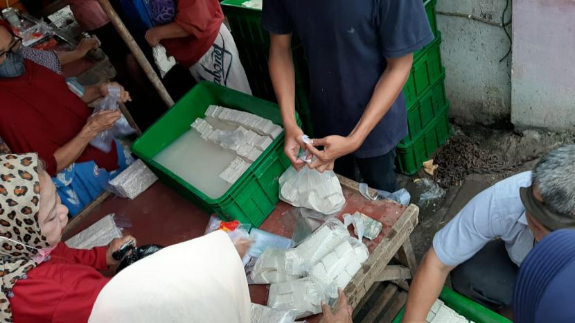 Nyoto Prawiro sedang membungkus tahu pesanan pembeli di lapaknya, PD Pasar Minggu, Jakarta Selatan, Ahad (3/1) sore. Nyoto adalah satu-satunya pedagang tahu dan tempe di PD Pasar Minggu pada hari ini. Sebab, sudah empat hari pengrajin tahu dan tempe mogok produksi lantaran harga kedelai naik hingga 35 persen.
